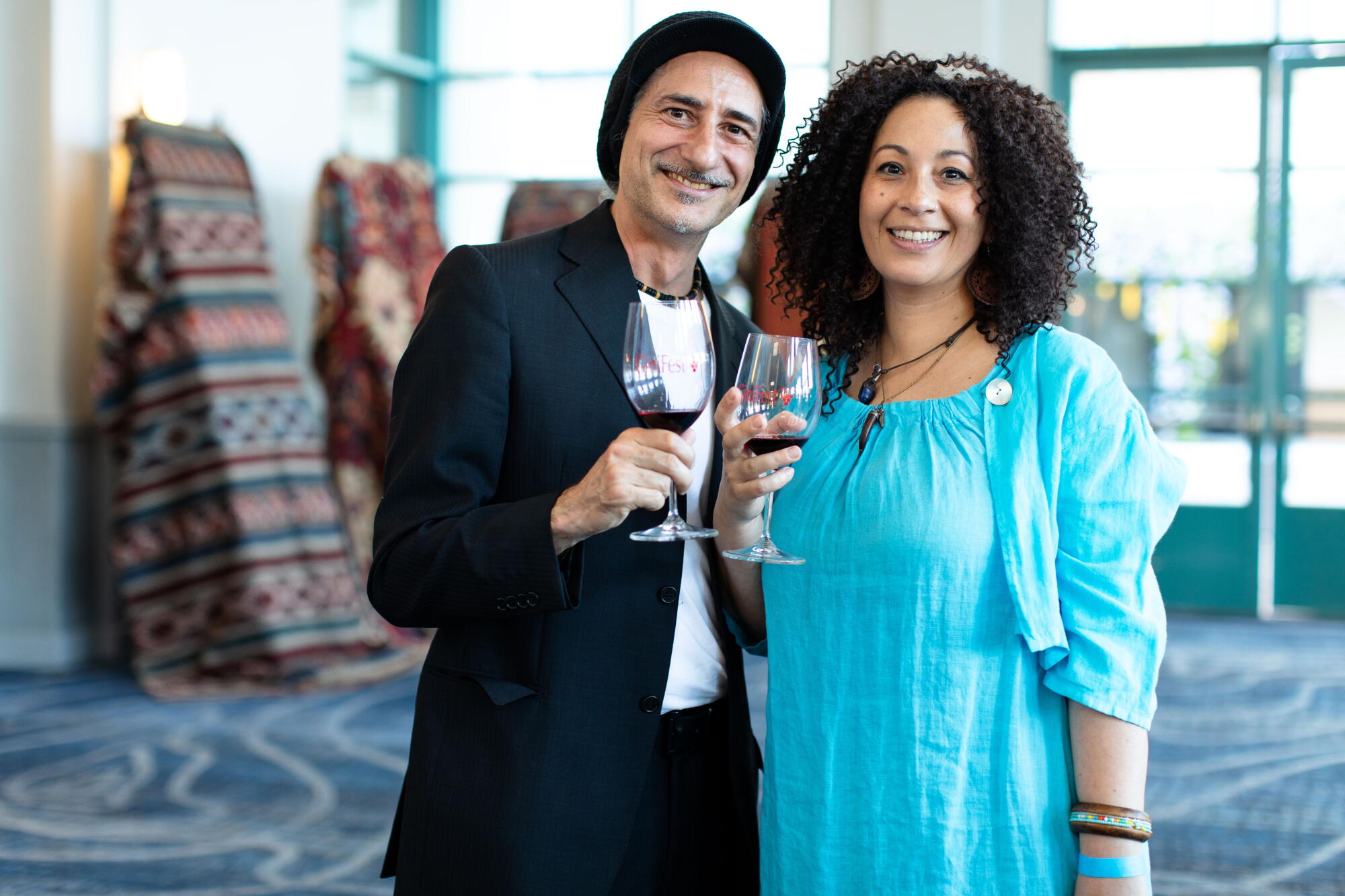 Two guests holding glasses of red wine at GiniFest 2023 in Burbank